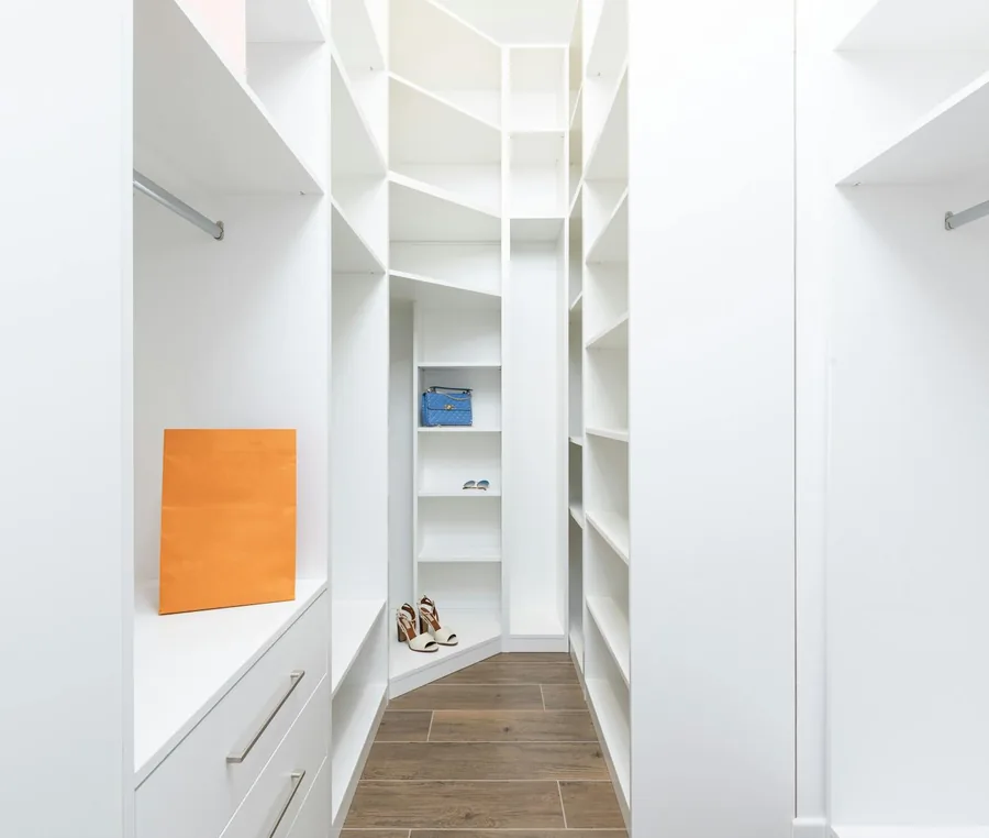 Custom walk-in wardrobe with white shelves and wood-finish flooring