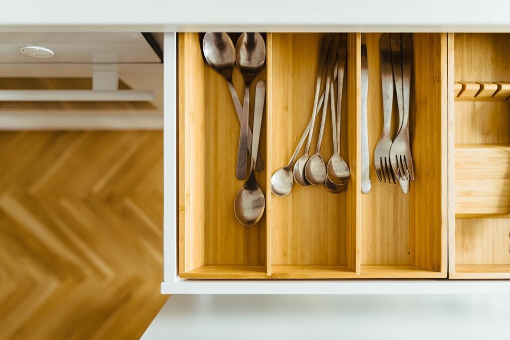 Open modular kitchen drawer with wooden cutlery organiser and soft-close runner